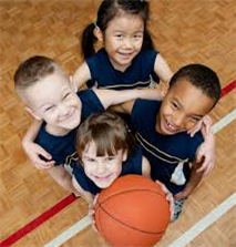 Four young kids holding a basketball looking up at a camera